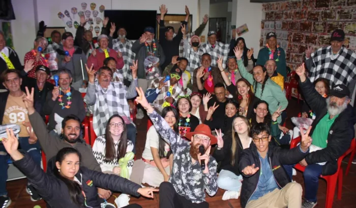 Grupo numeroso de personas reunidas y celebrando alegremente en un espacio interior con motivo de voluntariado y comunidad